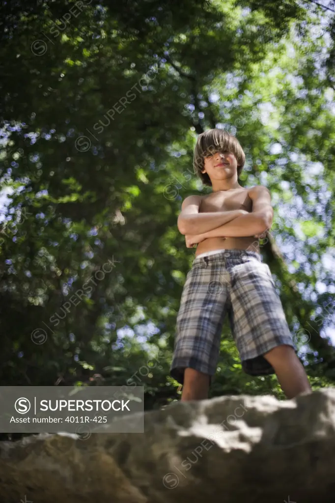 Portrait of boy standing on rock at creek