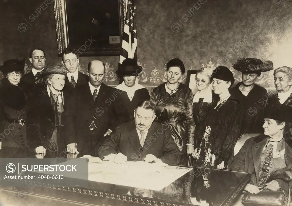 Men and women witness as Colorado governor, Oliver H. Shoup, signs a ratification document for the 19th amendment granting woman's suffrage. Dec. 12, 1919.