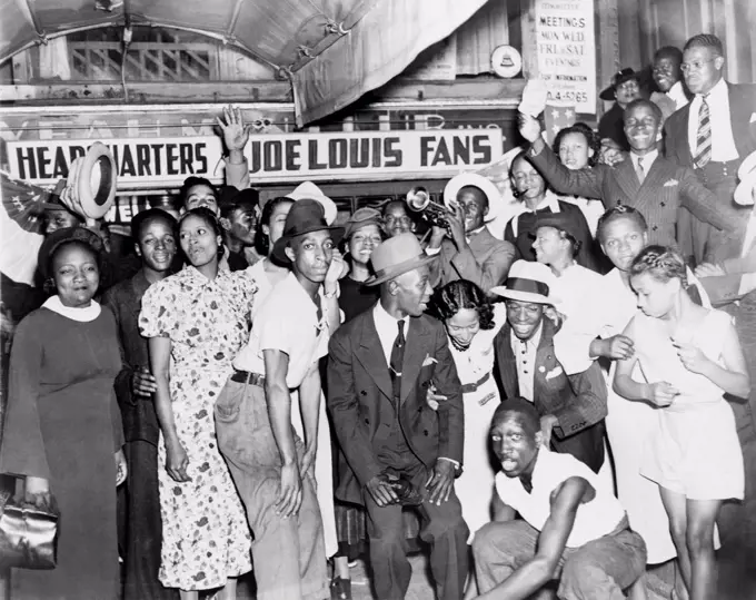 Joe Louis fans in front of fan headquarters to celebrate Louis' close decision victory over Tom Farr, the famous Welsh/British boxer. Harlem, New York City, August 30, 1937.