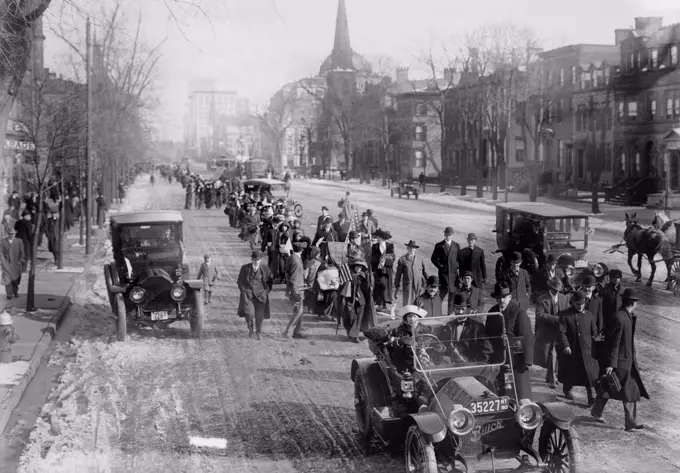 Suffrage hikers on way to Washington walking through Newark, New Jersey on Broad Street, February 12, 1913. The hike was organized and led by 'General' Rosalie Jones, leading behind the first car.