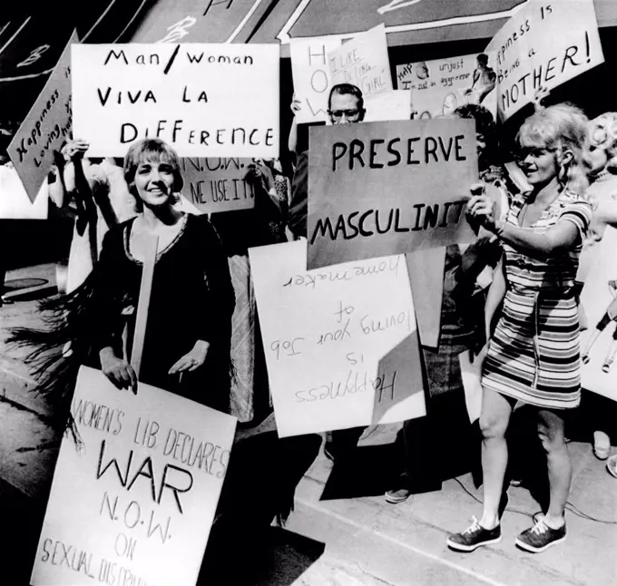 Anti-Women's Liberation protesters. They counter demonstrate with signs reading 'Viva la Difference', 'Preserve Masculinity', 'I like being a girl' and 'Happiness is being a mother.' A solitary feminist holds a sign, 'Women’s liberation declares war now on sexual discrimination.' Aug. 26, 1970.