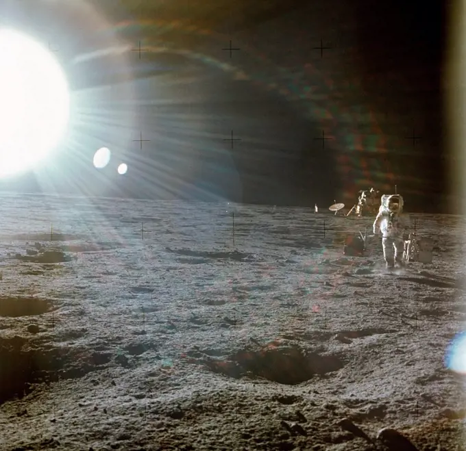 Apollo 12 Astronaut Alan Bean deploys scientific experiments on the lunar surface. The bright flare of light is caused by the Sun. The Lunar Lander is in the distance. Nov. 19, 1969.