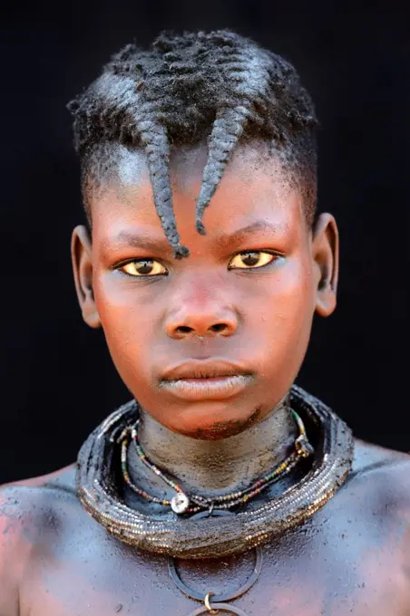 Portrait of Himba girl with the typical necklace and double plait hairstyle of the pre-adolescent. Kaokoland, Namibia. October 2015