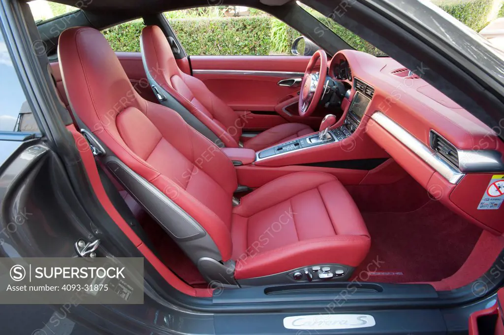 View of the red leather interior from the passenger's side of a 2012  Porsche 911 Carrera S. Porsche platform number 991 showing the steering  wheel, dashboard and seats. - SuperStock