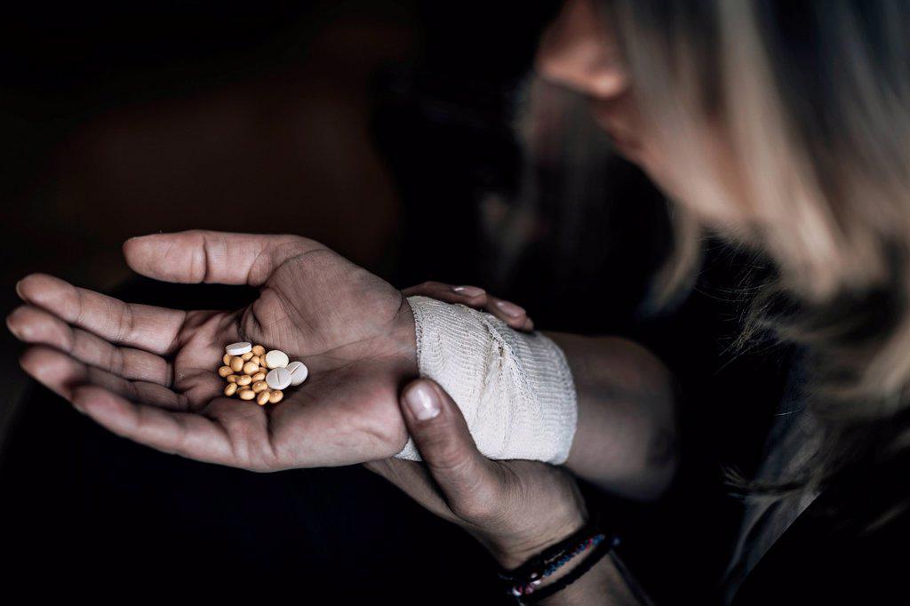 Suicidal woman holding number of pills in hand.