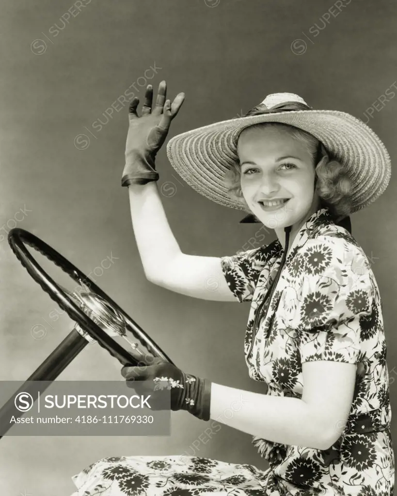 håndtag Ungdom shuffle 1930s 1940s SMILING WOMAN WEARING STRAW HAT SUN DRESS DRIVING GLOVES WAVING  HOLDING AUTOMOBILE STEERING WHEEL LOOKING AT CAMERA - SuperStock
