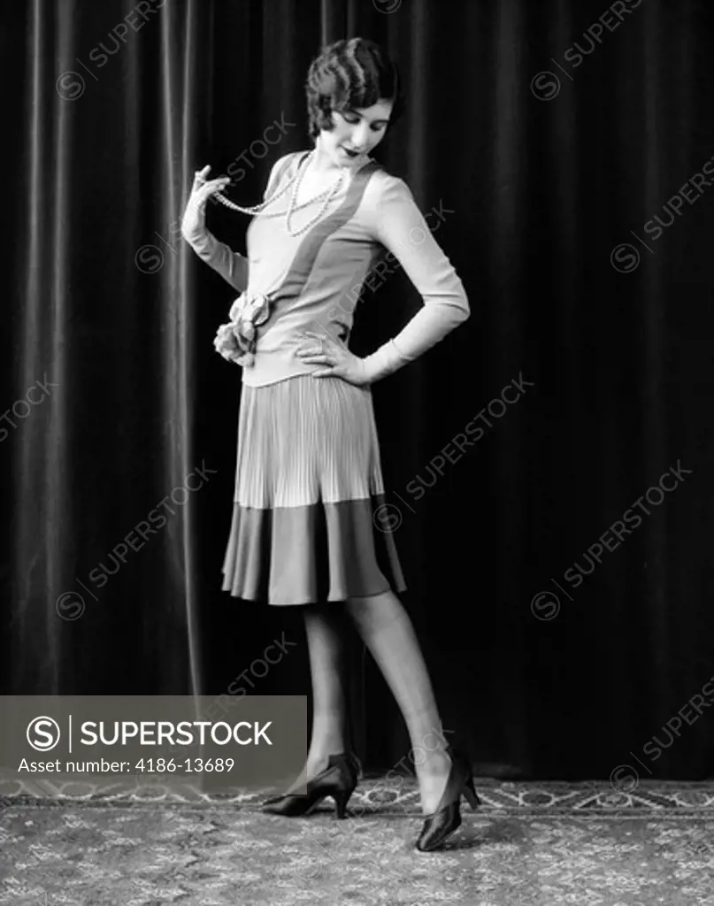 1920S Flapper Woman Posing Hand On Hip Holding String Of Pearls Stretching Leg Checking Hosiery Seams