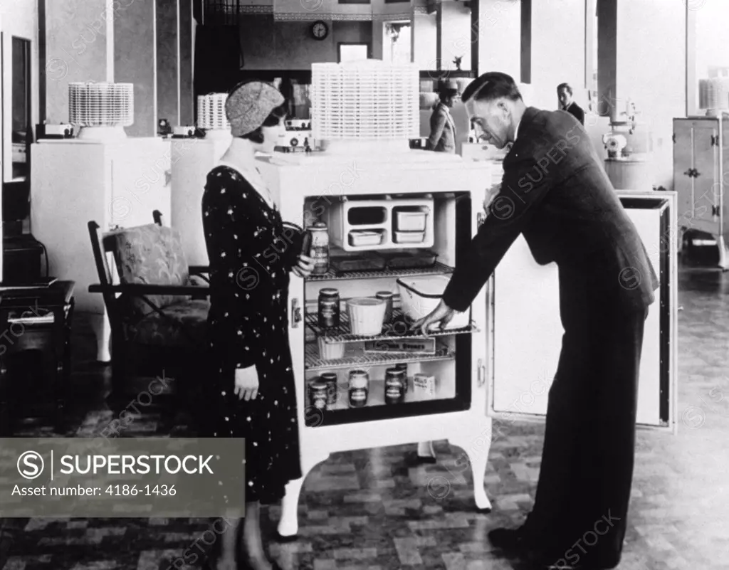 1920S 1930S Salesman Demonstrating Refrigerator To Woman Shopper