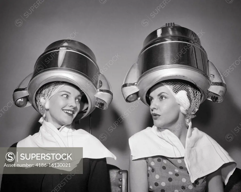 1950s TWO WOMEN SITTING UNDER BEAUTY SALON HAIR DRYERS WEARING HAIRNETS  TOWELS TALKING GOSSIP - SuperStock
