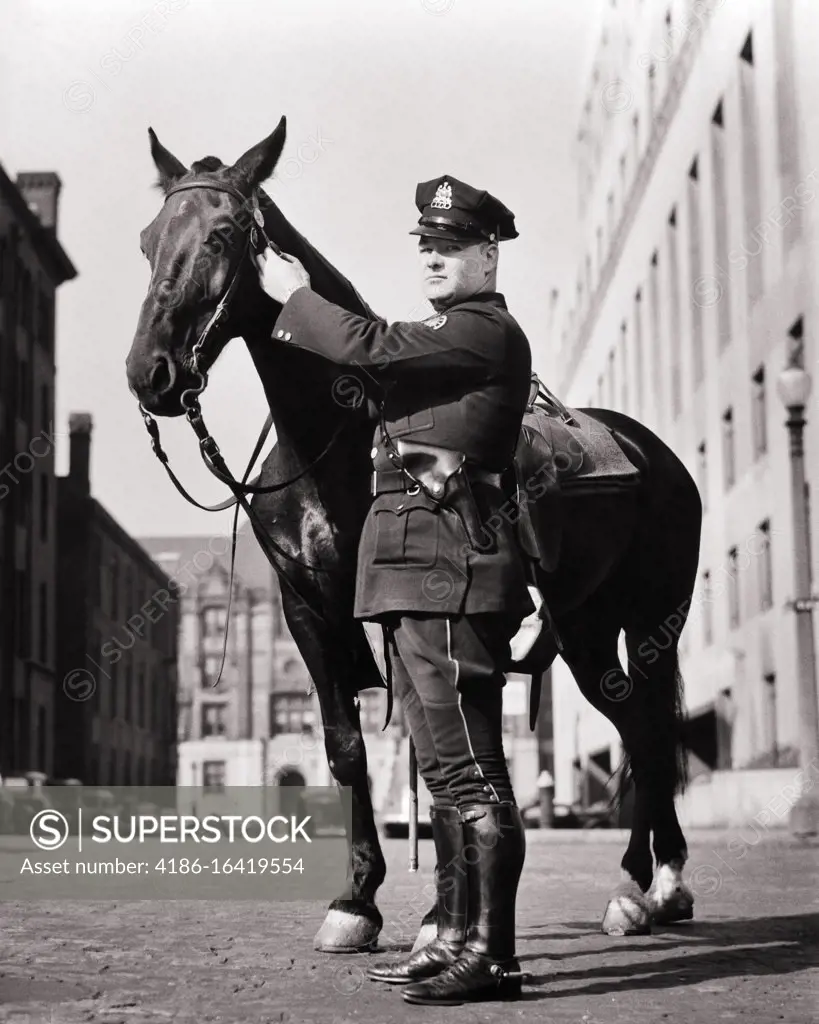 1930s 1940s UNIFORMED MOUNTED POLICEMAN STANDING NEXT TO HIS HORSE LOOKING AT CAMERA ST. LOUIS MISSOURI USA