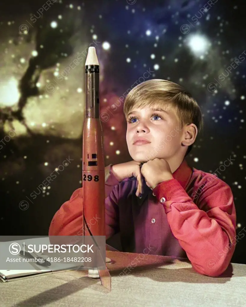 1960s DAY DREAMING BOY WITH MODEL ROCKET AND OUTER SPACE BACKGROUND