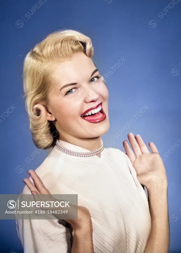 1950s HAPPY PROUD ELATED WOMAN WEARING PEARLS SMILING WITH HANDS UP THUMBS TUCKED UNDER ARMS LOOKING AT CAMERA