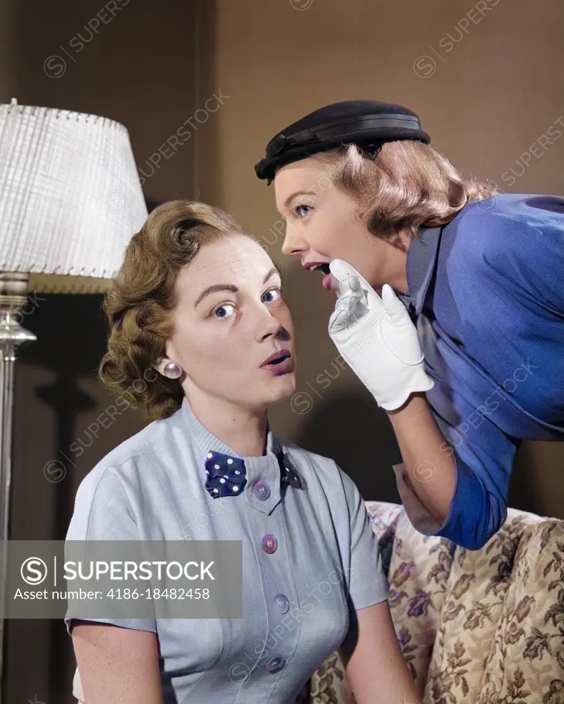 1950s WOMAN IN HAT & WHITE GLOVES LEANING DOWN TO WHISPER GOSSIP TO FRIEND
