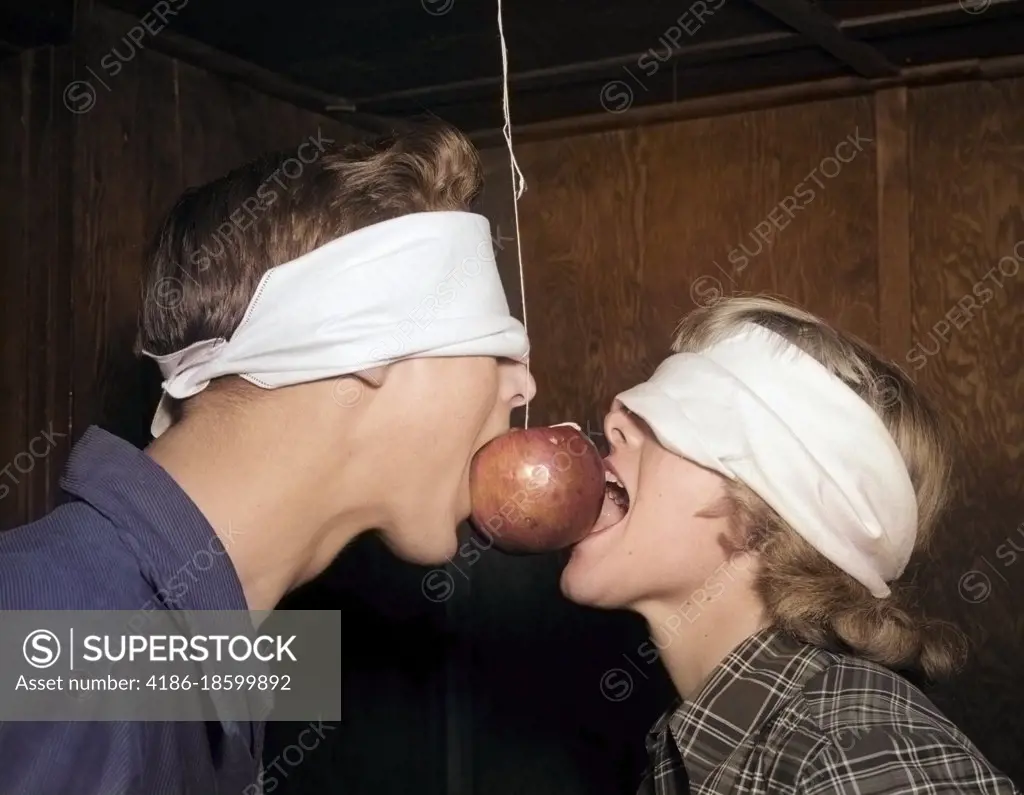 1950s BLINDFOLDED TEENAGE COUPLE BOY GIRL TRYING TO EAT AN APPLE HANGING ON A STRING