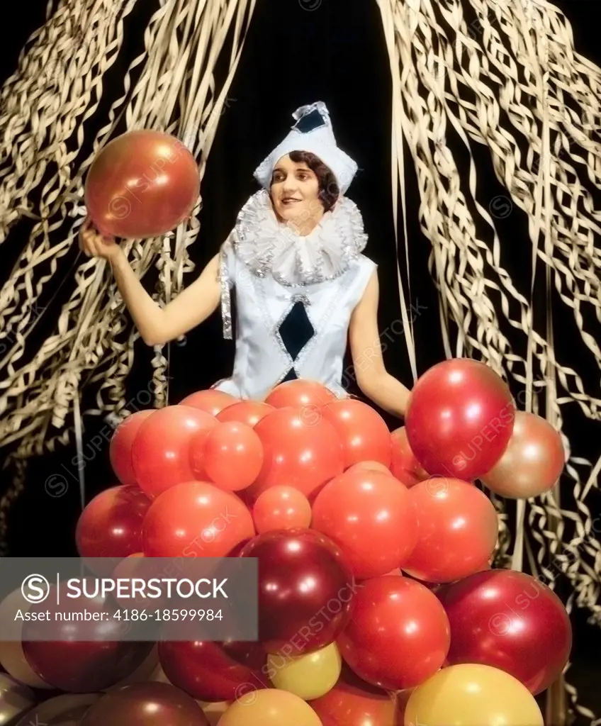 1920s 1930s SMILING YOUNG WOMAN Pierrot CLOWN AMID PARTY BALLOONS AND PAPER STREAMERS