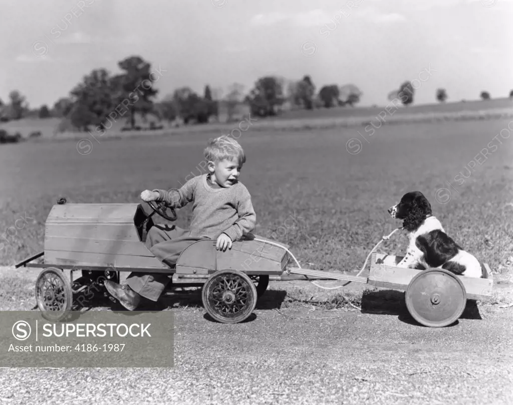 1930S 1940S Boy In Wooden Toy Car Pulling Dog Behind In Wagon