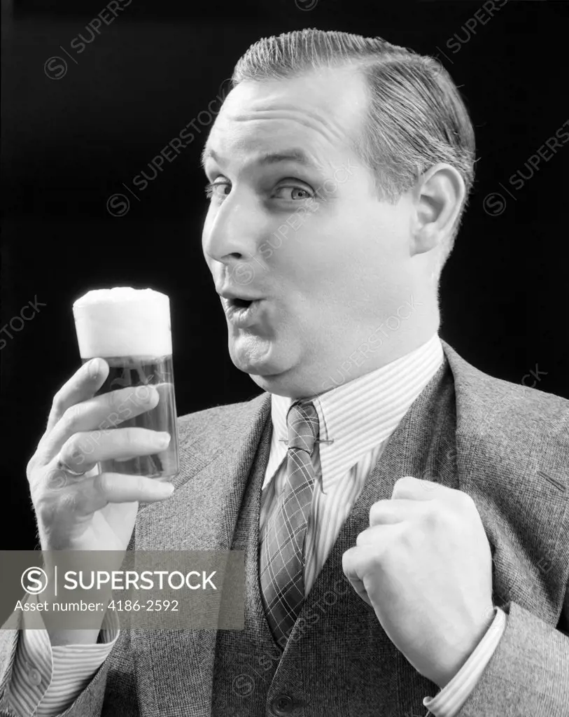 1930S Man Holding Full Foamy Glass Of Beer Making A Funny Face With His Thumb Hooked Confidently Under His Vest Looking At Camera