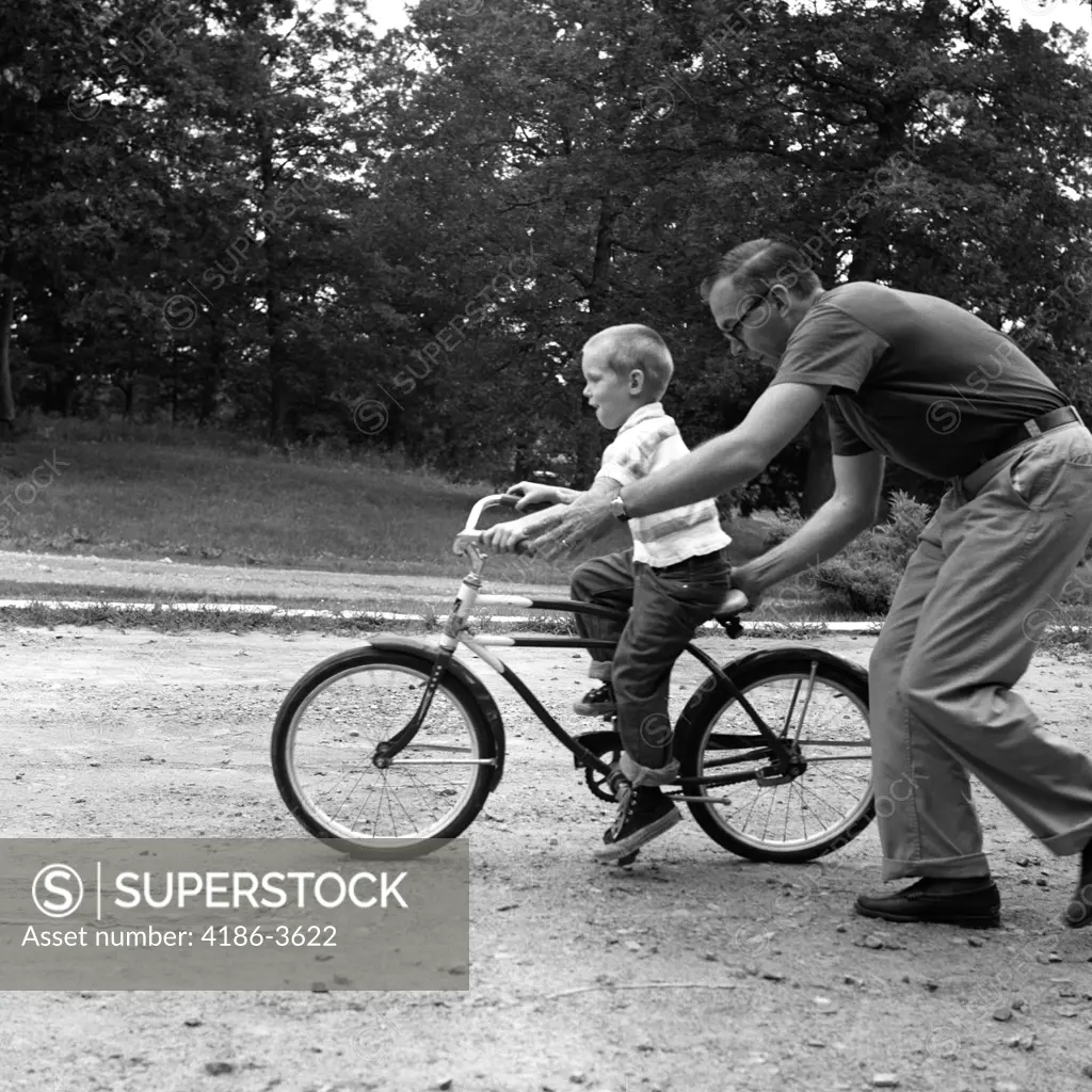 1960S Father Giving Son On Bike A Push Teaching Him How To Ride Bicycle
