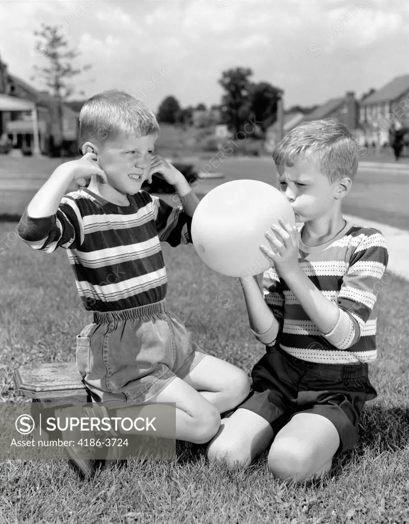 1950S Two Young Boys One Blowing Up Balloon One With Fingers In Ears Afraid Of Explosion