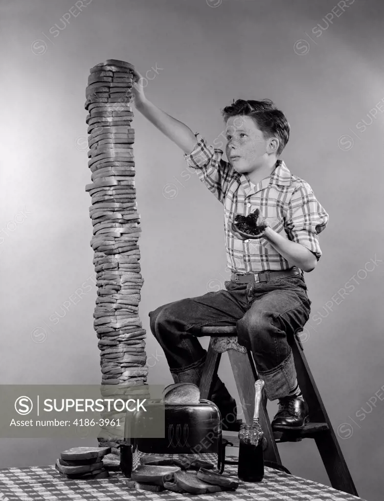 1950S Boy Eating Jelly Toast Sitting On Ladder Stacking Up Tall Pile Of Toast From Toaster