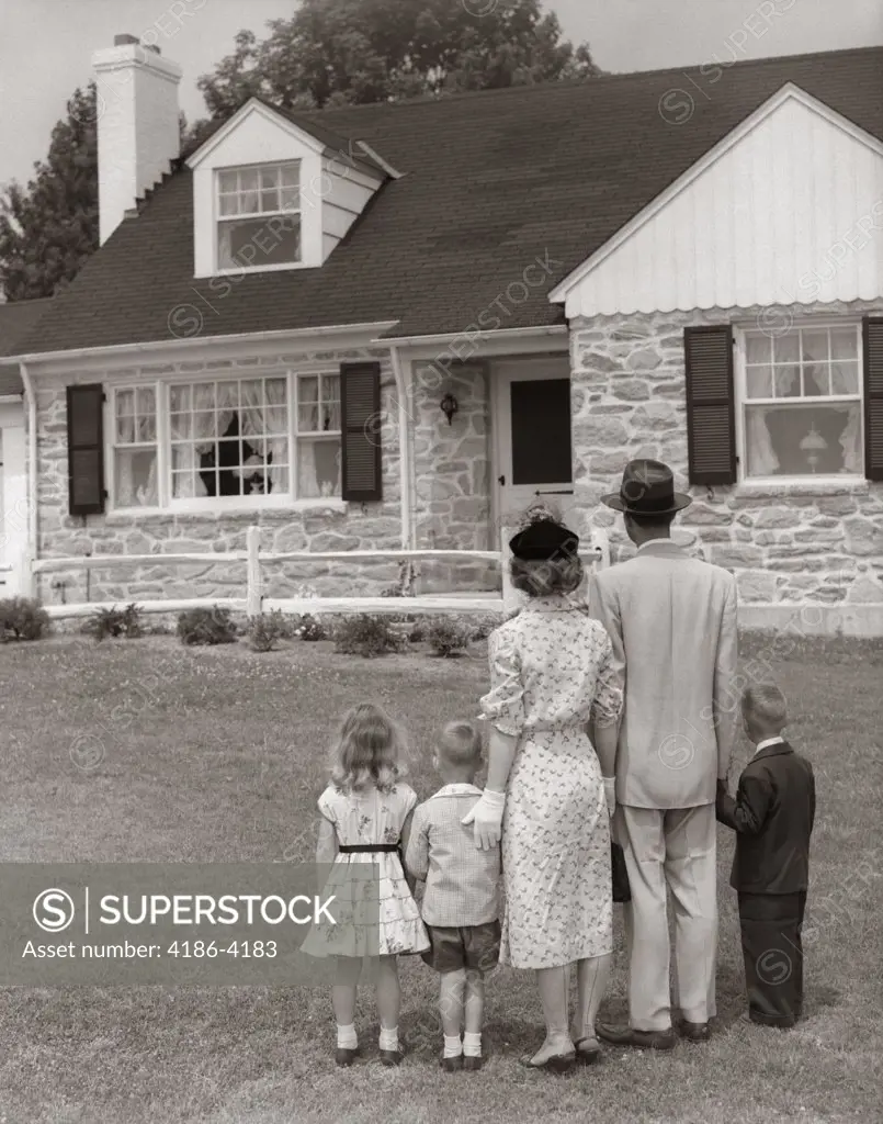 1950S Family Of Five With Backs To Camera On Lawn Looking At Fieldstone House