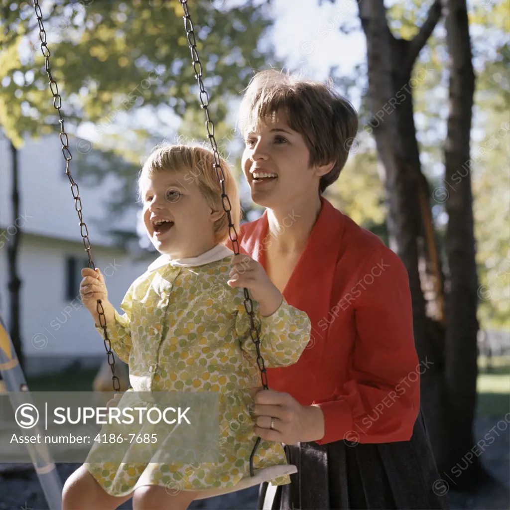 1960S 1970S Smiling Mother Pushing Laughing Girl Daughter On Backyard Swing