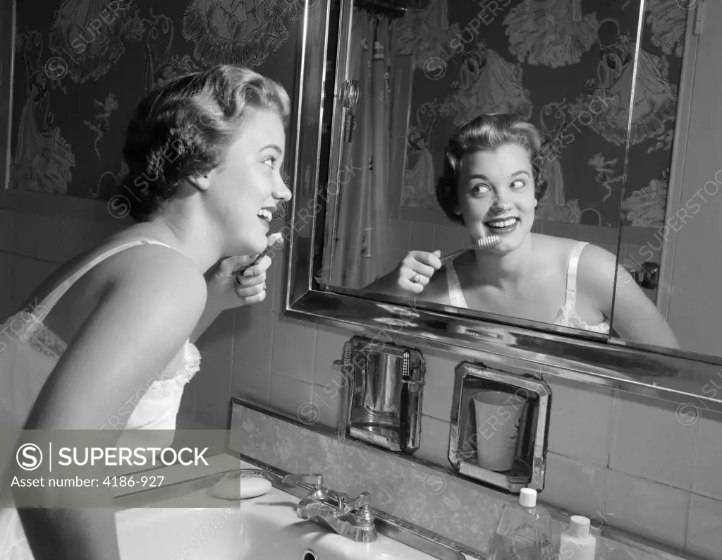 1950S Smiling Woman Looking Into Bathroom Mirror Brushing Teeth