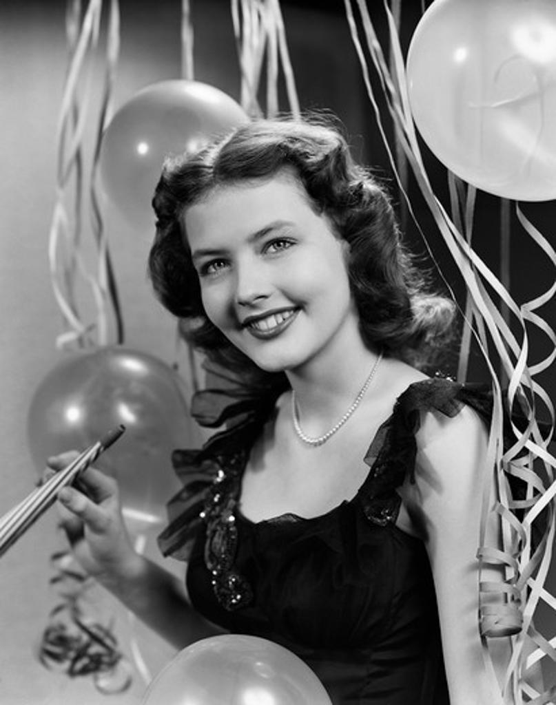 1940S 1950S Smiling Woman Black Party Dress Pearls Holding New Year Party Noise Maker Streamers Balloons Background