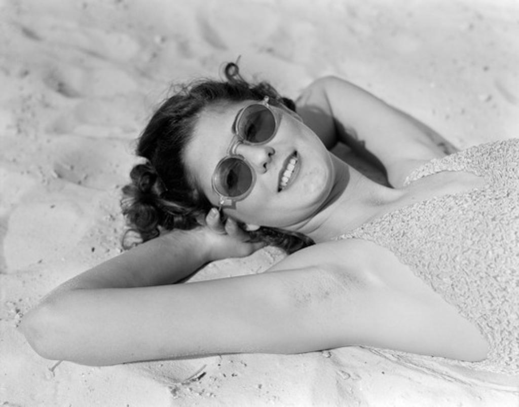 1930S Woman In Sunglasses Lying On Beach Wearing Bathing Suit