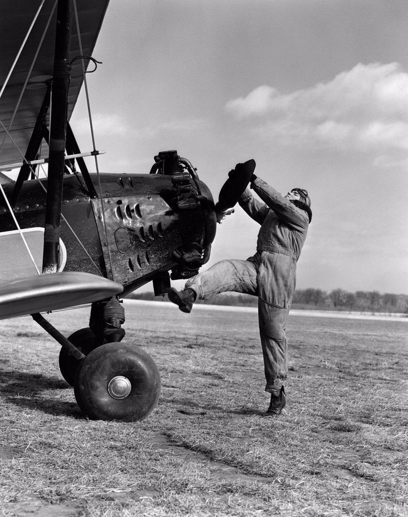 1920S Male Pilot Trying To Turn Plane'S Propeller By Hand