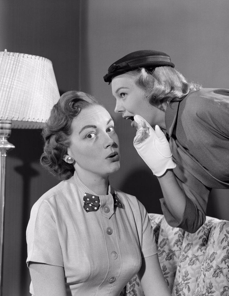 1950S Woman In Hat & White Gloves Leaning Down To Whisper Gossip To Friend