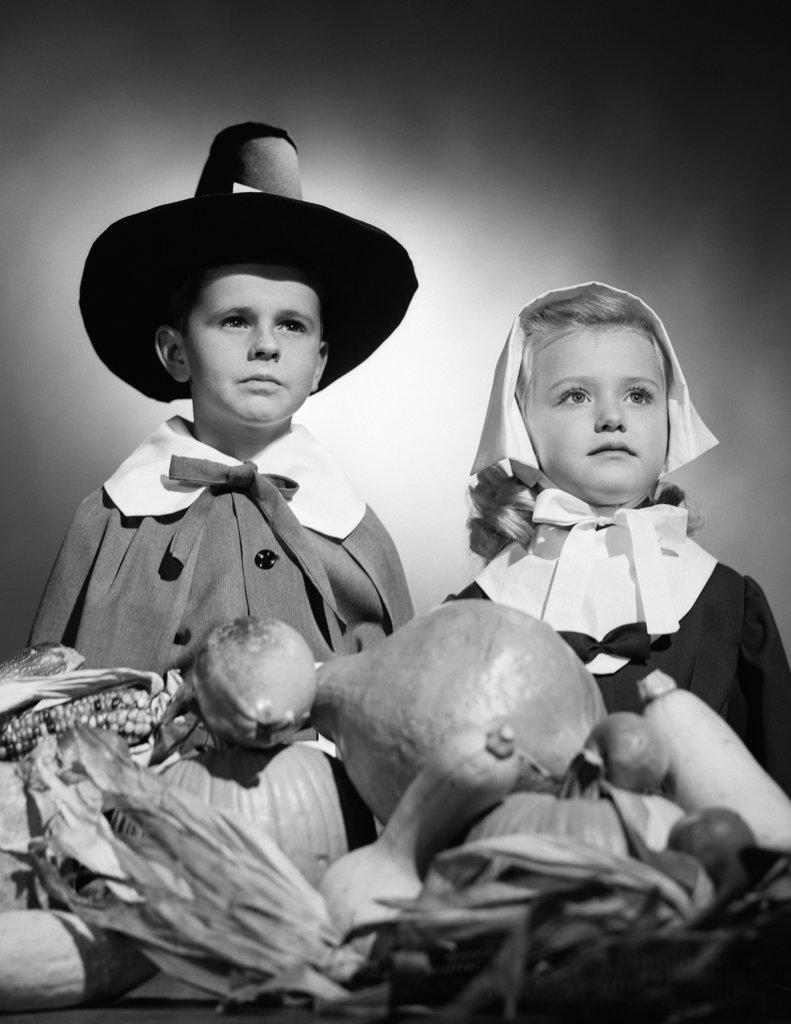 1950S Boy & Girl In Pilgrim Costumes With Harvest On Table In Front Of Them