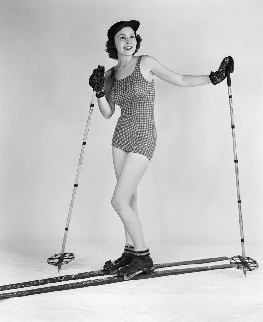 1930S Smiling Woman Posing In Studio On Wood Skis Wearing Bathing Suit Ski Hat Gloves Boots Holding Bamboo Ski Poles