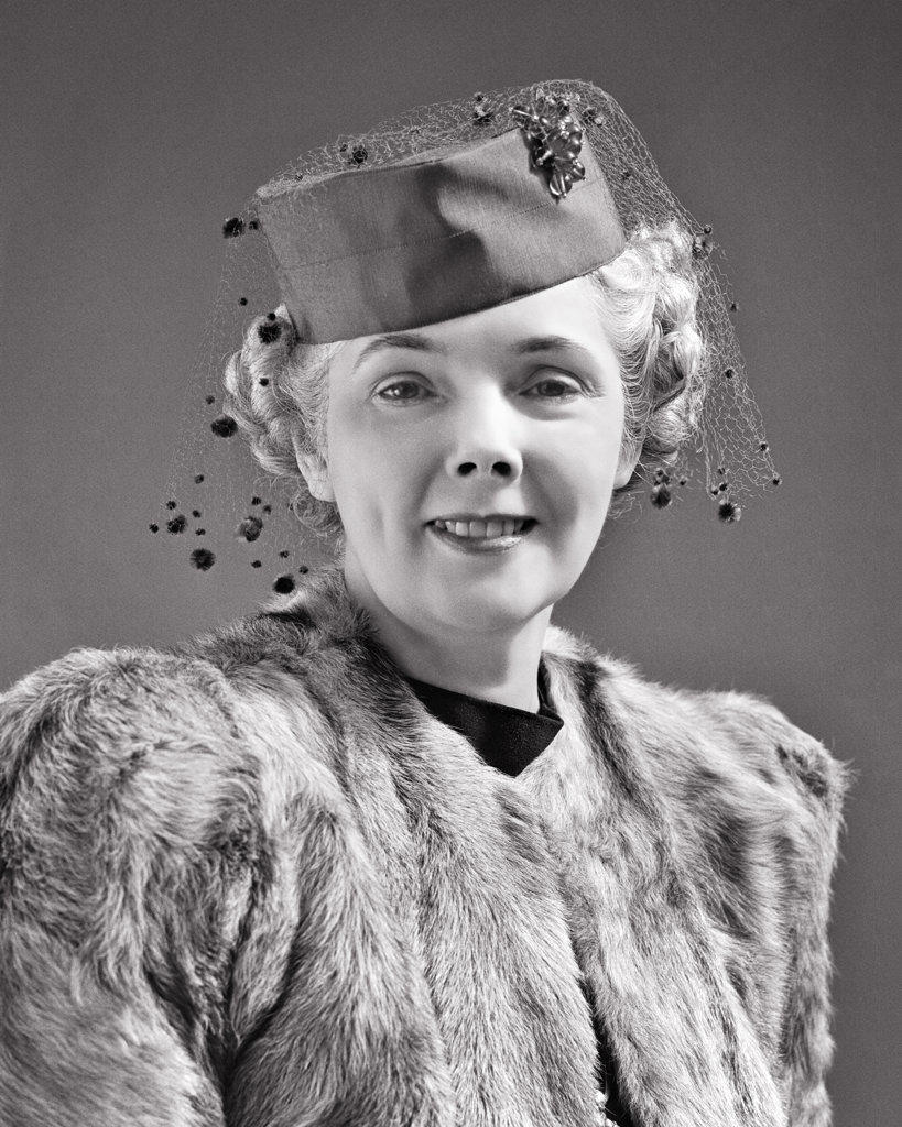 1940s SMILING ELEGANT MATURE SENIOR WOMAN LOOKING AT CAMERA WEARING FUR COAT AND PILLBOX HAT WITH VEIL AND BROOCH 