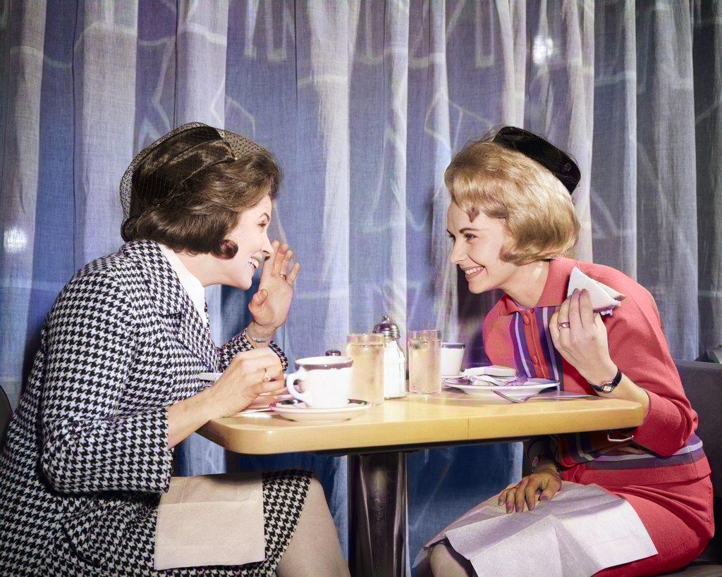 1960s TWO WOMEN GOSSIPING AT LUNCH IN RESTAURANT