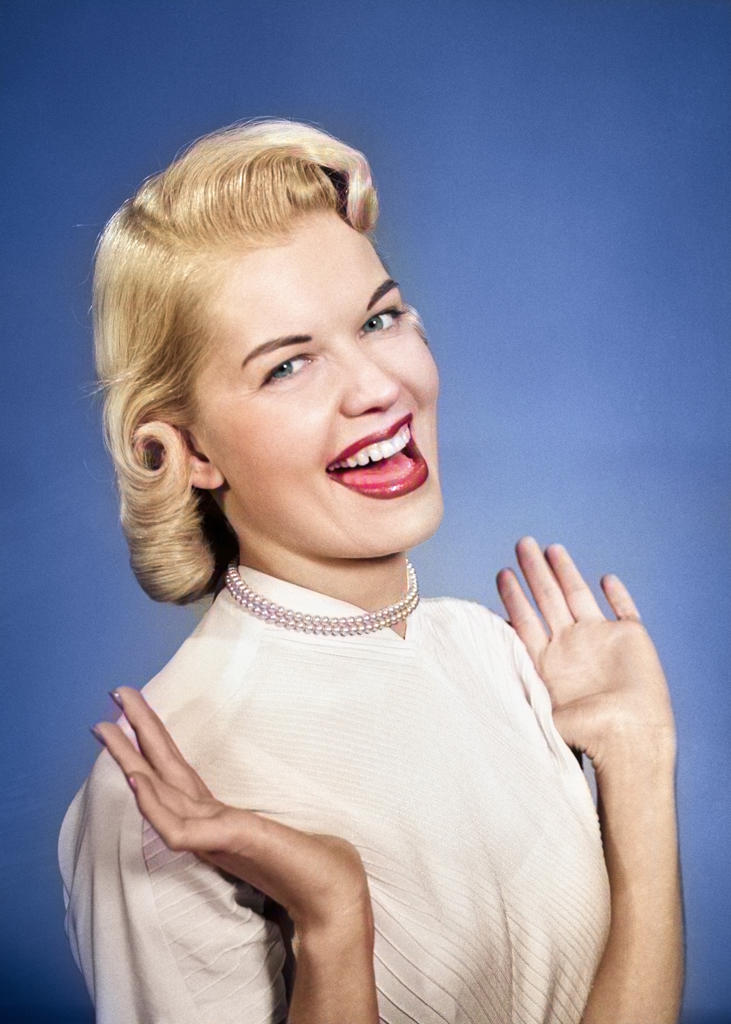 1950s HAPPY PROUD ELATED WOMAN WEARING PEARLS SMILING WITH HANDS UP THUMBS TUCKED UNDER ARMS LOOKING AT CAMERA