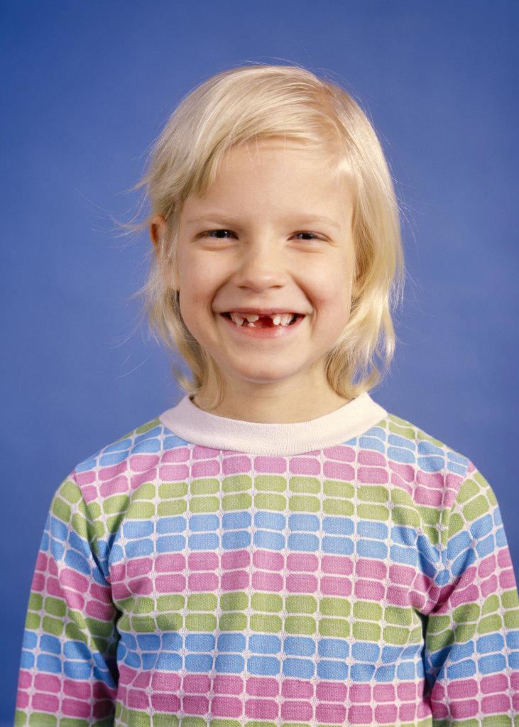 1970s SMILING BLOND GIRL MISSING HER FRONT TEETH LOOKING AT CAMERA WEARING PASTEL STRIPED SHIRT