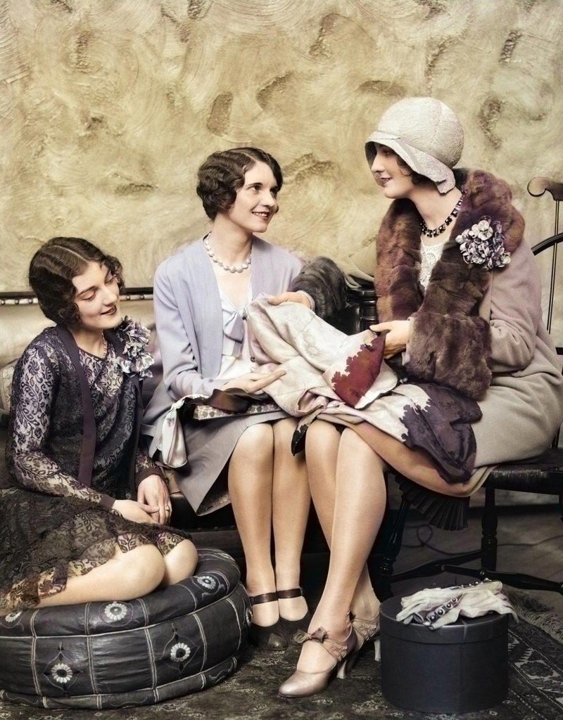 1920s WOMAN IN COAT & HAT BACK FROM SHOPPING SHOWING NEW PURCHASES TO TWO FRIENDS