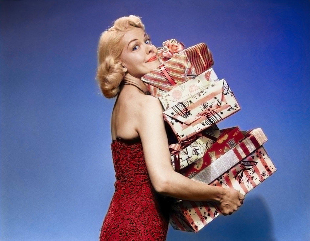 1950s BLOND WOMAN STRAPLESS DRESS CARRYING STACK GIFT WRAPPED PRESENTS CHRISTMAS PACKAGES LOOKING AT CAMERA