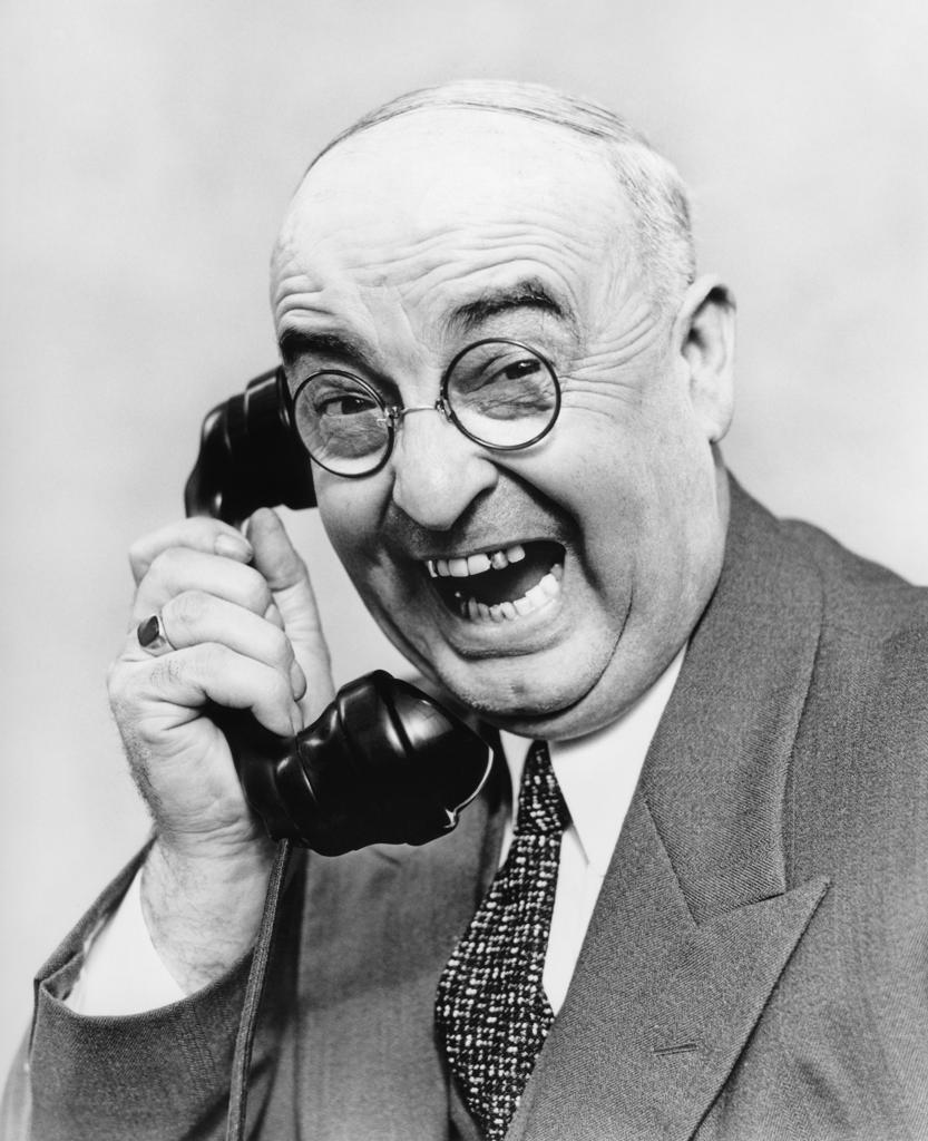 1930s SENIOR MAN WITH PINCE NEZ EYEGLASSES AND BAD TEETH LAUGHING TALKING ON TELEPHONE LOOKING AT CAMERA