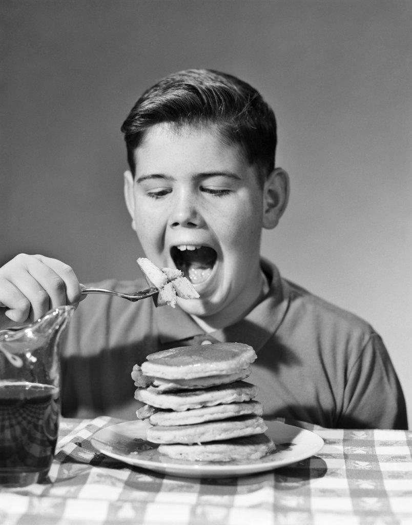 1960s BOY EATING STACK OF PANCAKES 
