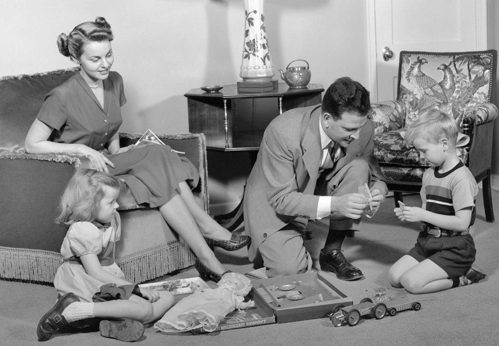1940s FAMILY FATHER MOTHER DAUGHTER SON TOGETHER IN LIVING ROOM WITH TOY ERECTOR SET