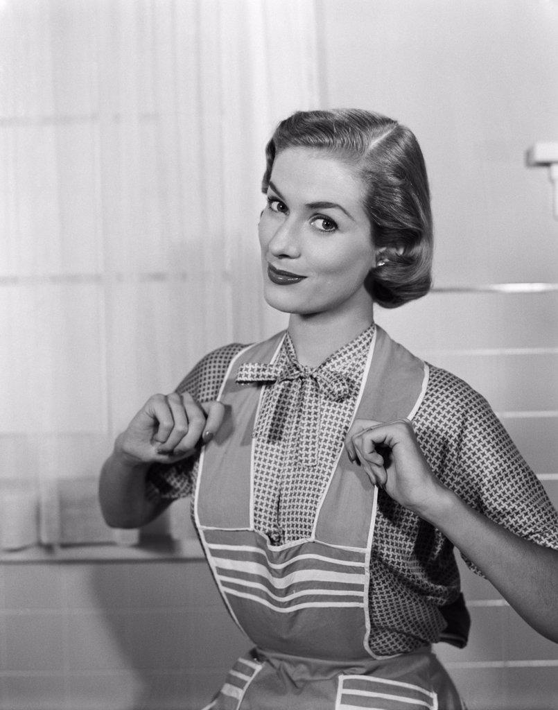 1950S Housewife Wearing Apron With Thumbs Proudly Hooked On Straps