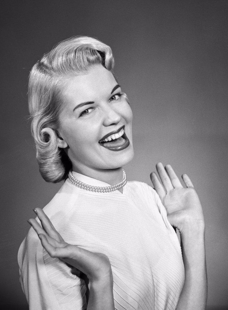 1950S Woman Wearing Pearls Smiling With Hands Up Thumbs Tucked Under Arm