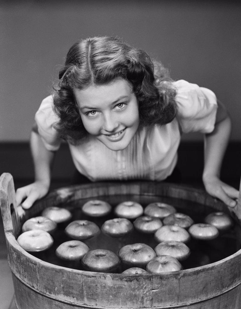 1940S Smiling Teen Girl Leaning Over Tub About To Begin Bobbing For Apples Floating In The Water