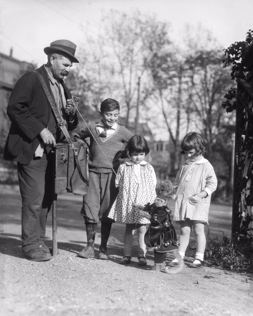 1920S Group Of Three Children Watching Organ Grinder'S Monkey In Costume Standing On Hind Legs