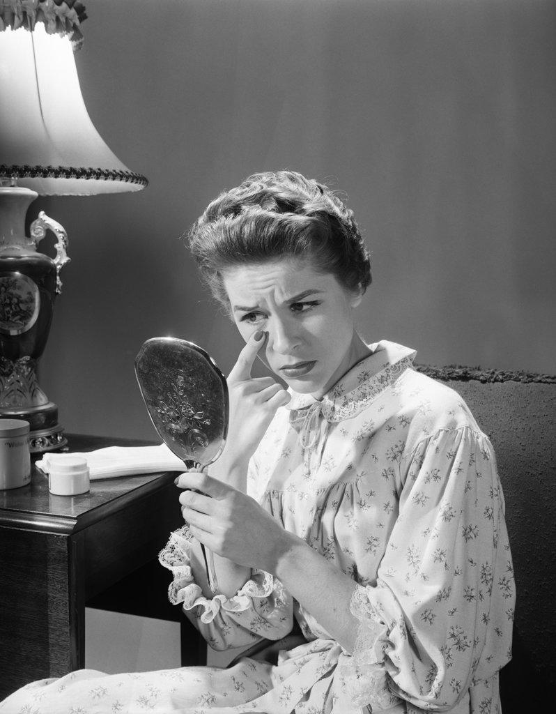 1950S 1960S Woman In Nightgown Holding Mirror Look At Eye Wrinkles Aging Beauty Cosmetic Serious Concerned Expression