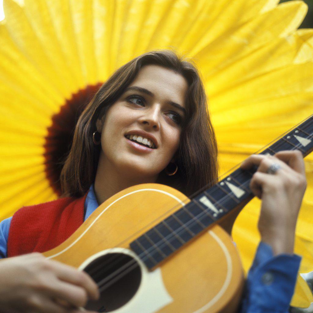 1970S Smiling Teenaged Girl Playing Acoustic Guitar With Large Yellow Sunflower Backdrop
