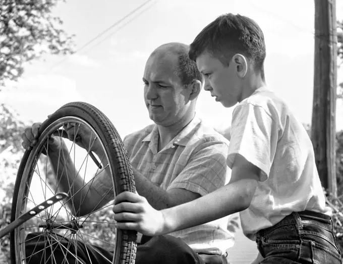 1950s 1960s FATHER AND SON FIXING TIRE ON BICYCLE