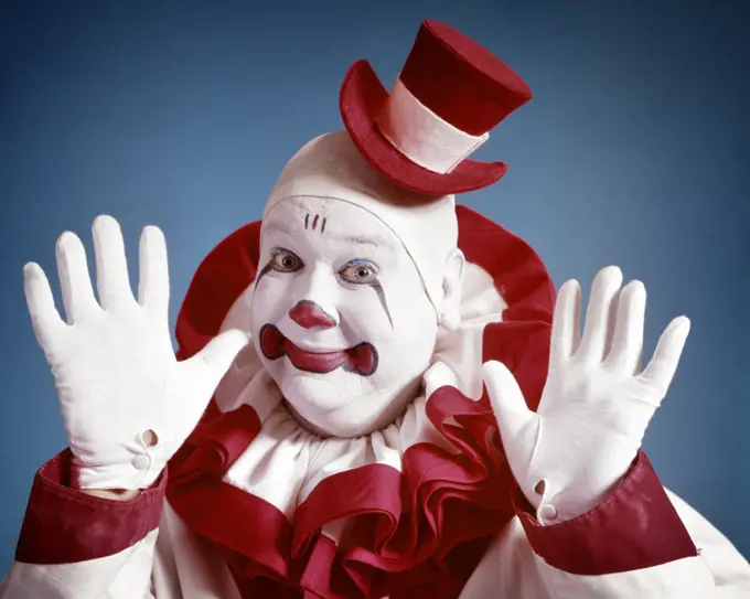 1970s SMILING PORTRAIT OF CLOWN LOOKING AT CAMERA WEARING TINY TOP HAT HOLDING UP HAPPY HANDS IN WHITE GLOVES